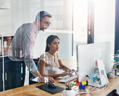 Tech professional helping office worker with computer