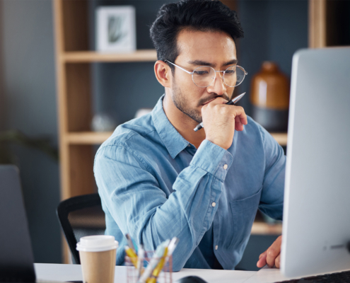 Serious, business man and thinking on computer in office
