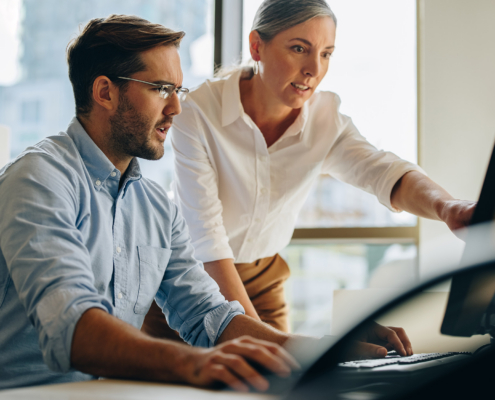 two workers look at computer